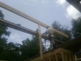 Carpenter setting a ridge beam over a new addition frame — Ice Dam Removal by Roofing Brothers in Northport