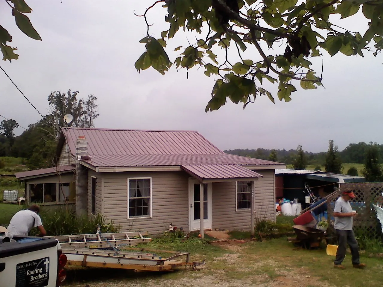 Crew finishing a mauve metal roof on a small farmhouse in Northport
